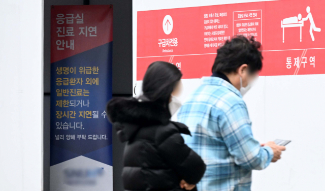 전공의들이 의대 정원 확대에 반발하며 집단행동을 예고한 가운데 시민들이 18일 서울의 한 대학병원 응급실에 설치된 진료 지연 안내문 앞을 지나가고 있다. 권욱 기자