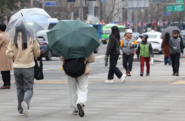 18일 오후 서울 종로구 광화문광장에서 시민들이 우산을 쓰고 걸어가고 있다. 연합뉴스