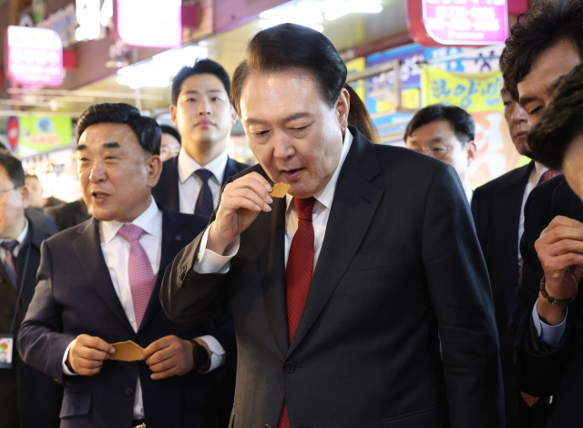 윤석열 대통령이 21일 울산시 남구 신정상가시장을 찾아 옛날과자 가게에서 과자를 맛보고 있다. 연합뉴스