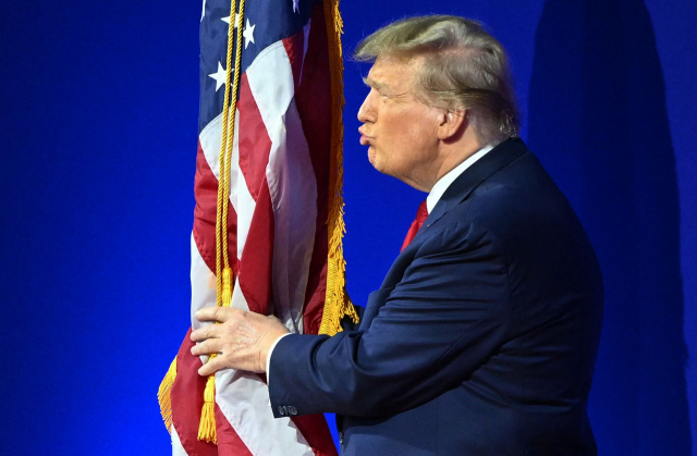 도널드 트럼프 전 대통령이 24일(현지 시간) 미국 워싱턴DC 인근에서 열린 ‘보수정치행동회의(CPAC·시팩)’ 행사의 연단에 오르며 성조기에 키스하고 있다.AFP연합뉴스