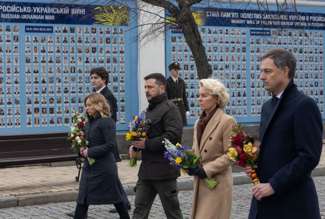 러시아·우크라이나 전쟁이 발발한 지 2년이 된 24일(현지 시간) 볼로디미르 젤렌스키 우크라이나 대통령과 서방 지도자들이 우크라이나 키이우에 있는 '전사자 추모의 벽'에 헌화하기 위해 꽃을 들고 걸어가고 있다. 쥐스탱 트뤼도(왼쪽부터) 캐나다 총리, 조르자 멜로니 이탈리아 총리, 젤렌스키 대통령, 우르줄라 폰데어라이엔 유럽연합(EU) 집행위원장, 알렉산더르 더크로 벨기에 총리. AFP연합뉴스