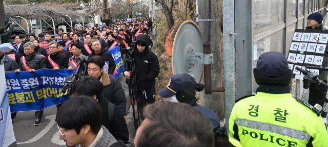 전공의들의 집단행동 엿새째인 25일 김택우 대한의사협회 비상대책위원장을 비롯한 의사들이 서울 용산구 대한의사협회 회관에서 용산 대통령실을 향해 가두 행진을 출발한 가운데 한 시민이 의사들을 규탄하는 피켓을 들고 이들을 바라보고 있다. 오승현 기자 2024.02.25