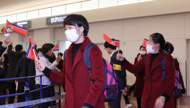 붉은색 코트를 입은 북한 여자 축구 대표팀 선수들이 25일 도쿄 하네다공항을 통해 일본에 입국하고 있다./연합뉴스