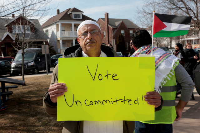 25일(현지 시간) 미국 미시간주에서 아랍계 유권자들이 팔레스타인 지지 집회를 열고 있는 가운데 한 남성이 민주당 경선에서 ‘지지 후보 없음’에 투표를 하자는 팻말을 들고 있다. 로이터연합뉴스