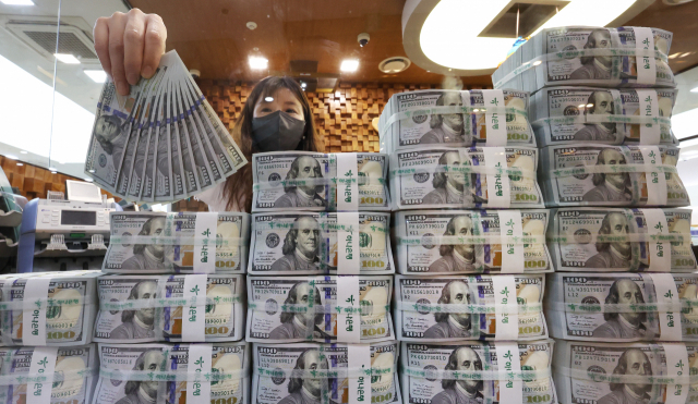 서울 명동 하나은행 위변조대응센터에서 직원이 미국 달러를 들어 보이고 있다. 연합뉴스