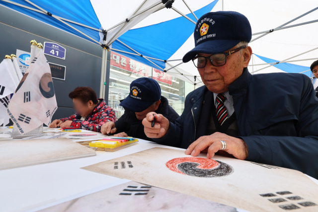 지난 2월 29일 서울 은평구 권애란로에서 열린 진관사 태극기 그리기 행사에서 한국전쟁 참전용사들이 진관사 태극기를 그리고 있다. 연합뉴스