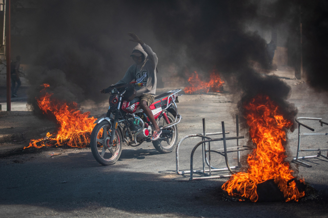 1일(현지시간) 아이티 포르토프랭스에서 오토바이를 탄 사람이 아수라장이 된 도로의 불길을 뚫고 지나가고 있다. EPA연합뉴스