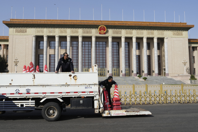 중국 교통경찰들이 2일 양회(전국인민대표대회·전국인민정치협상회의)가 열리는 베이징 인민대회당 앞에 주차 금지 안전 고깔을 설치하고 있다. AP연합뉴스