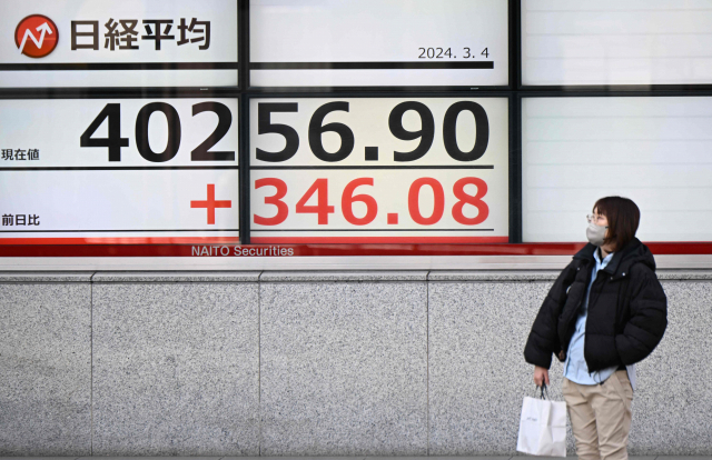 한 여성이 일본 닛케이225지수를 알리는 전광판을 지켜보고 있다. 이날 닛케이지수는 사상 처음으로 4만 선을 넘어섰다. AFP연합뉴스