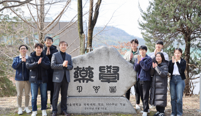 김대덕(왼쪽 네 번째) 교수가 ‘서울대 약대 개교 100주년 기념탑’을 배경으로 연구원들과 손뼉을 치고 있다.