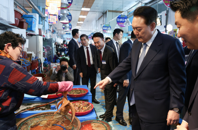 윤석열 대통령이 13일 경남 사천시 삼천포용궁수산시장을 찾아 한 점포에서 문어를 살펴보고 있다. 사천=연합뉴스