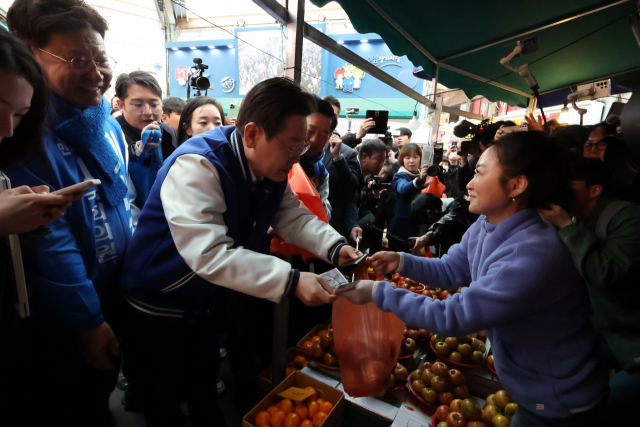 15일 오전 울산 남구 수암시장을 방문한 이재명 더불어민주당 대표가 시장에서 사과를 구매하고 있다. 연합뉴스