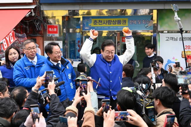 이재명 더불어민주당 대표가 19일 오전 강원 춘천시 중앙시장을 방문해 시민들에게 받은 과일을 들고 인사하고 있다. 연합뉴스