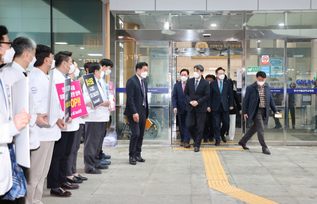 이주호 사회부총리 겸 교육부 장관과 조규홍 보건복지부 장관 등이 25일 경남 진주 경상국립대를 방문해 박완수 경남도지사와 의대 증원 준비사항을 점검한 가운데 병원 앞에서 경상대 의대와 병원 교수 비상대책위원회가 필수의료 대책을 요구하고 있다. 사진제공=경남