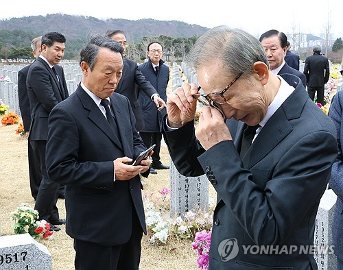 이명박 전 대통령이 25일 오전 국립대전현충원 천안함 46용사 묘역을 찾아 참배 후 묘비 주변을 확인하다 눈가를 닦고 있다. 연합뉴스