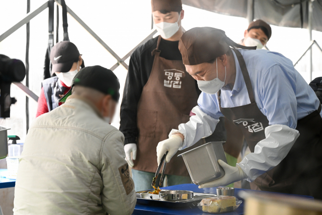 윤석열 대통령이 27일 서울 명동성당 내 무료 급식소인 '명동밥집' 야외 배식장에서 봉사활동을 펼치며 추가 배식을 하고 있다. 연합뉴스