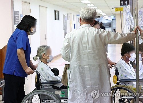 전공의 집단행동이 이어지고 있는 22일 오전 서울 시내 한 의사가 환자들의 엘리베이터 탑승을 도와주고 있다. 연합뉴스