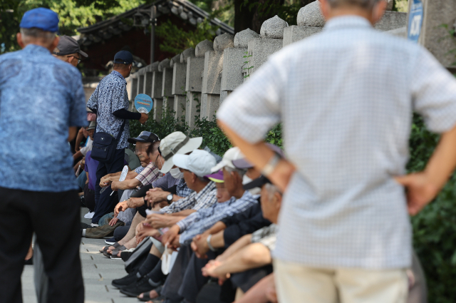 서울 종로구 탑골공원에서 어르신들이 햇볕을 피해 무료 급식을 기다리고 있다. 연합뉴스