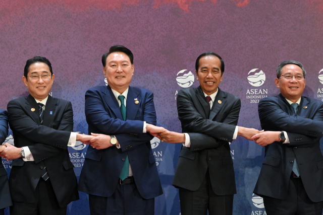 윤석열 대통령이 지난해 9월 인도네시아 자카르타에서 열린 아세안+3(한중일) 정상회의에서 기시다 후미오(왼쪽) 일본 총리, 리창(오른쪽) 중국 총리, 조코 위도도 인도네시아 대통령과 손을 맞잡고 있다. 연합뉴스