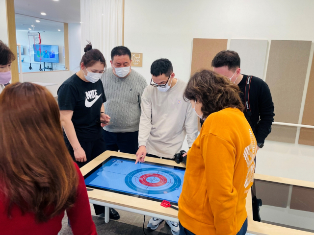 몽골 울란바토르 시의회 관계자들이 스마트테이블 기구로 인지 재활 프로그램인 2인 컬링 게임을 체험하고 있다. 사진 제공=케어링
