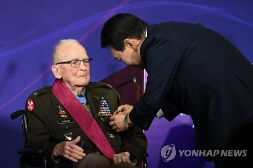 2023년 4월 25일 미국을 국빈 방문한 윤석열 대통령이 워싱턴DC 한 호텔에서 열린 한국전 참전용사 오찬에서 참전용사인 랄프 퍼켓 예비역 육군 대령에게 태극무공훈장을 친수하고 있다. 연합뉴스