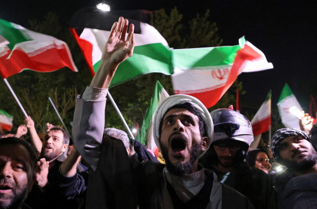 이란이 이스라엘에 드론과 미사일 공격을 가한 후 14일 테헤란 주재 영국 대사관 앞에 모인 시위자들이 이란의 국기와 팔레스타인 국기를 흔들고 있다. AFP연