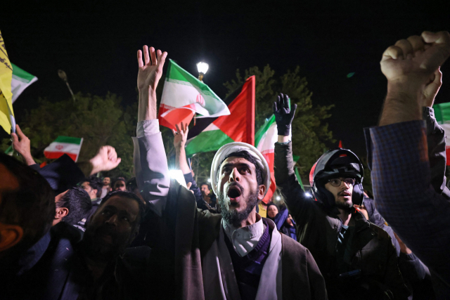 이란 국민들이 14일 테헤란의 영국 대사관 앞에 모여 이란 국기와 팔레스타인 국기를 흔들며 이란의 공습을 지지하고 있다. AFP연합뉴스