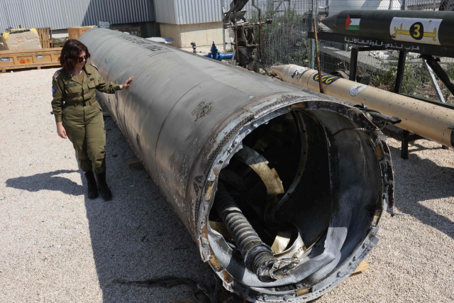 16일(현지 시간) 이스라엘 남부 도시 키랴트말라치 인근 줄리스 군사기지에서 한 이스라엘 군인이 탄도미사일 잔해 옆에 서 있다. 이스라엘군은 이란이 14일 이스라엘을 향해 발사한 탄도미사일을 사해에서 회수했다며 이날 언론에 공개했다. AFP연합뉴스