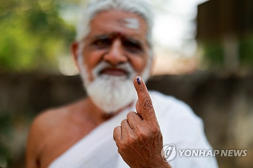19일 인도 타밀나두주 티루반나말라이의 한 투표소에서 힌두교 성직자가 투표를 마친 후 특수 잉크가 묻은 손가락을 보이고 있다. 인도는 중복 투표를 막기 위해 기표한 유권자의 손가락에 한동안 지워지지 않는 잉크를 묻힌다. 로이터 연합뉴스