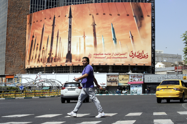 19일(현지시간) 이란 테헤란 거리에서 한 남성이 미사일과 페르시아어로 '이스라엘은 거미집보다 약하다'라는 문장이 적힌 반이스라엘 광고판을 지나가고 있다. EPA연합뉴스