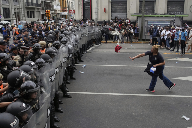 지난달 18일 아르헨티나 부에노스아이레스에서 한 여성이 무료급식소의 식량 부족 등을 항의하며 시위대를 막는 경찰을 향해 쓰레기 봉투를 던지고 있다. AP연합뉴스