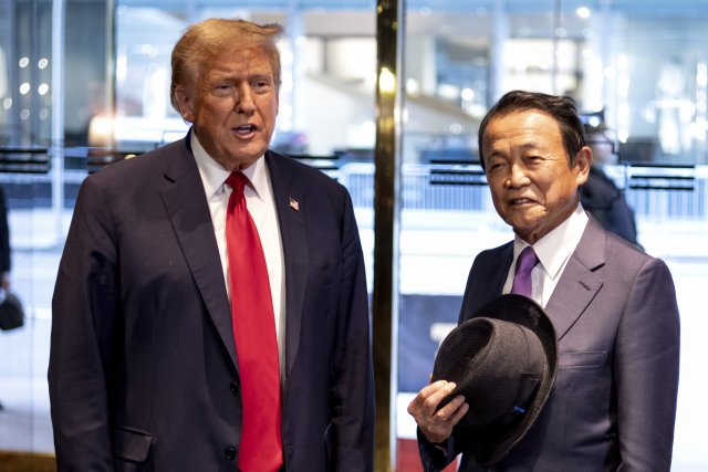 미국 공화당 대선 후보인 도널드 트럼프(왼쪽) 전 미국 대통령이 23일(현지시간) 뉴욕 트럼프 타워에서 그를 만나기 위해 방문한 아소 다소 일본 자민당 부총재를 맞이하고 있다./AP연합뉴스