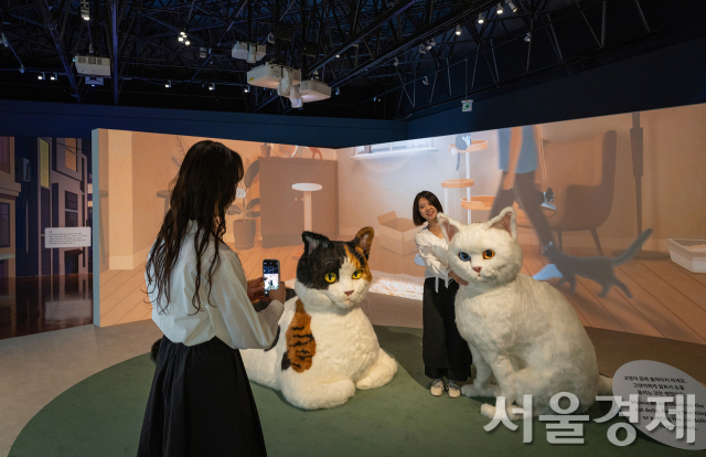 국립민속박물관의 ‘요물, 우리를 홀린 고양이’ 특별전에서 관람객들이 고양이 모형과 기념촬영을 하고 있다. 사진 제공=국립민속박물관