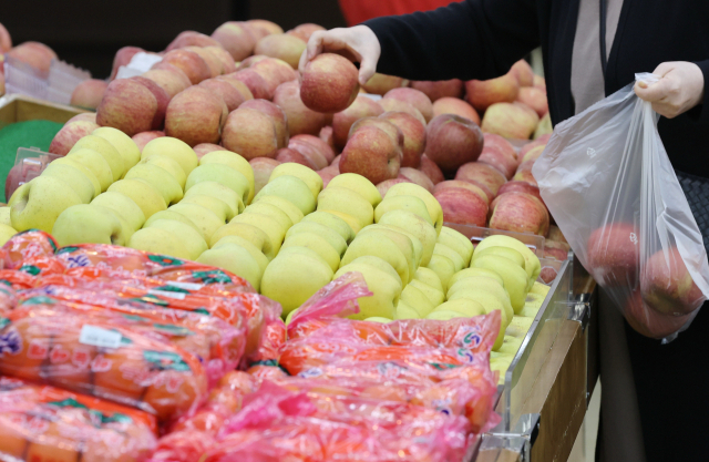 소비자가 서울의 한 대형마트에 진열된 사과를 집고 있다. 연합뉴스