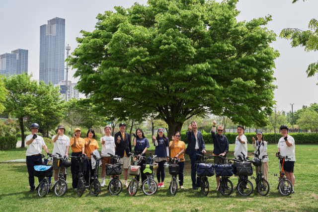 윌 버틀러 아담스(오른쪽에서 다섯번째) 브롬톤 CEO가 브롬톤 유저들과 자전거 앞에서 포즈를 취하고 있다. /사진 제공=더네이쳐홀딩스