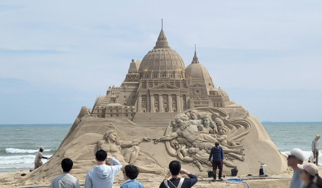 부산 해운대해수욕장에서 나들이객들이 대형 모래조각 작품을 보면서 걸어가고 있다. 연합뉴스