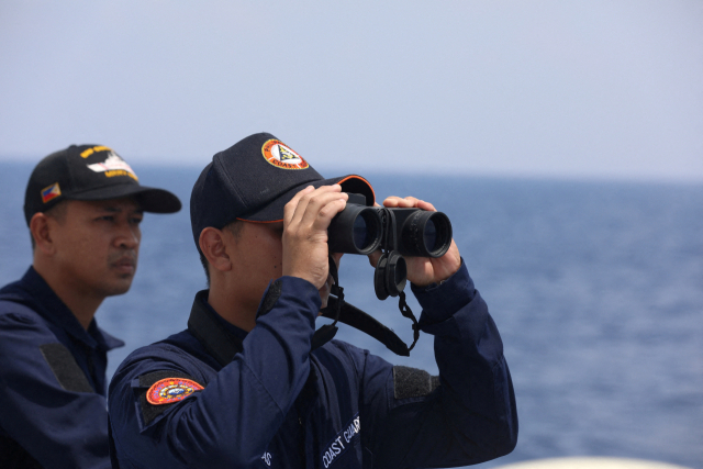 필리핀 해안경비대가 남중국해에 지상 군함에 주둔하고 있는 필리핀군을 위한 재보급 임무를 수행하며 쌍안경으로 주변을 둘러보고 있다. 로이터연합뉴스