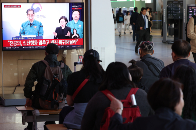 16일 오후 서울역에서 시민들이 한덕수 국무총리의 '의대 정원 관련 대국민담화' 발표를 방송으로 지켜보고 있다. 연합뉴스