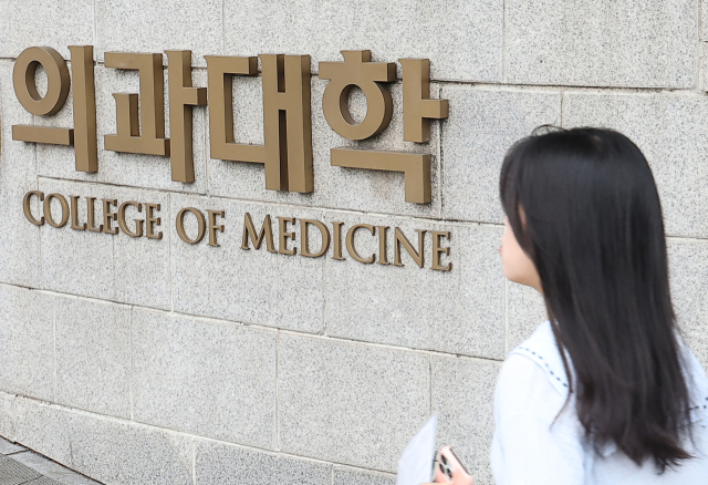 27년 만의 의대 입학정원 증원이 확정된 24일 시민들이 서울 시내 한 의과대학 인근을 지나고 있다. 한국대학교육협의회는 이날 대입전형위원회를 열고 각 대학이 제출한 2025학년도 대입전형 시행계획 변경 사항을 심의·확정했다. 연합뉴스