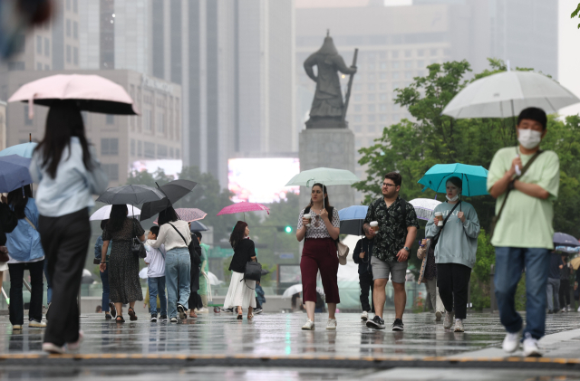 26일 오후 비가 내리는 서울 광화문광장에서 시민들이 우산을 쓴 채 걸어가고 있다. 연합뉴스