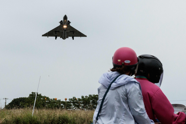 지난 23일 대만 북부 신추의 공군기지에서 대만 공군 소속 전투기가 착륙하고 있는 장면을 주민들이 오토바이에 탄 채 지켜보고 있다. AFP연합뉴스