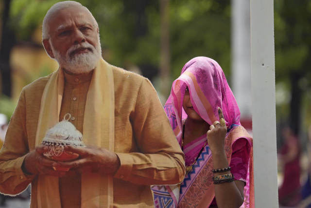 한 여성인 지난 1일(현지시간) 인도 바라나시에서 대선 투표 후 나렌드라 모디 인도 총리의 초상화 옆에서 사진을 찍으며 투표 잉크가 뭍은 집게손가락을 들어 보이고 있다. AP연합뉴스