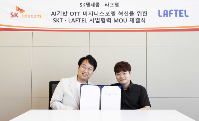 김혁(왼쪽) SKT 미디어제휴 담당(CMBO과 박종원 라프텔 대표가 3일 서울 여의도 라프텔 여의도 본사에서 업무협약을 체결한 뒤 협약서를 들어 보이고 있다. 사진 제공=SK텔레콤