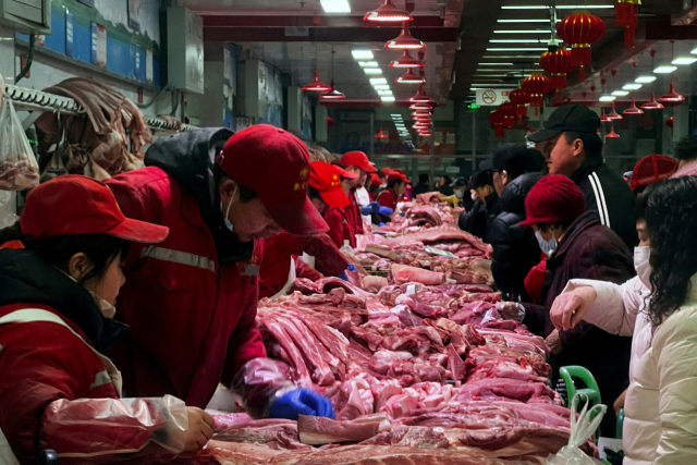 중국 베이징 신파디 도매 시장에서 2월 2일 돼지고기 판매상인들이 고객들과 흥정하고 있다. 로이터연합