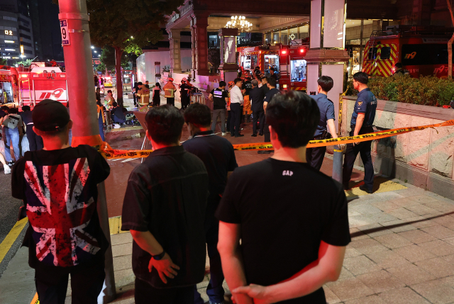 19일 오후 서울 강남구 논현동 한 호텔에서 화재가 발생해 소방당국이 진화 작업을 하는 가운데 20일 0시 40분께 시민들이 현장을 지켜보고 있다.연합뉴스