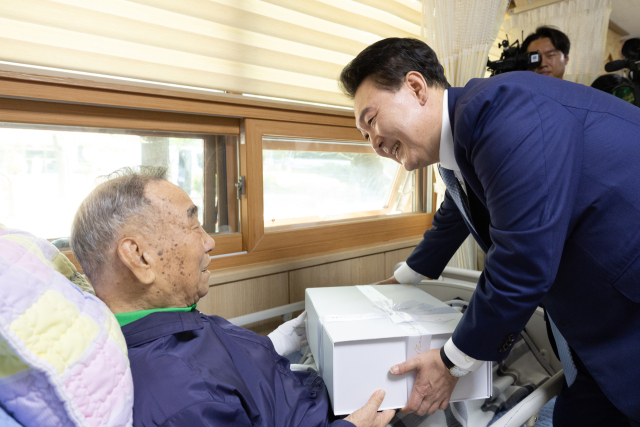 윤석열 대통령이 21일 경기도 수원보훈요양원을 방문해 한 국가유공자에게 '영웅의 제복'을 선물하고 있다. 연합뉴스