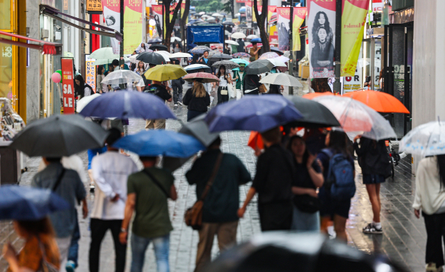 지난 22일 오전 서울 명동거리에 시민들과 관광객들이 우산을 쓰고 이동하고 있다, 연합뉴스