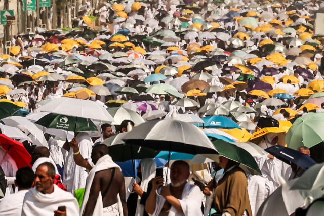하지 기간 중 사우디아라비아에 도착한 이슬람 순례자들이 아라파트산(자비의 산) 인근에 도착해 햇빛을 가리기 위해 우산을 들고 서 있다. AFP연합뉴스