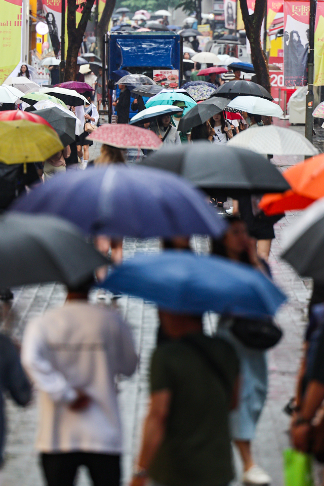 비가 내린 22일 서울 명동거리에 시민들과 관광객들이 우산을 쓰고 이동하고 있다, 연합뉴스