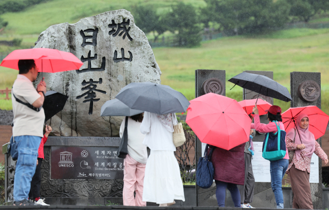 제주도에 호우주의보가 내려진 27일 오전 우산을 쓴 외국인 관광객들이 서귀포시 성산읍 성산일출봉을 탐방하고 있다.연합뉴스